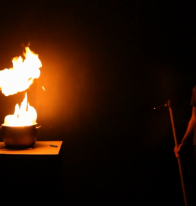 A science presenter safely observes the burning of a fuel